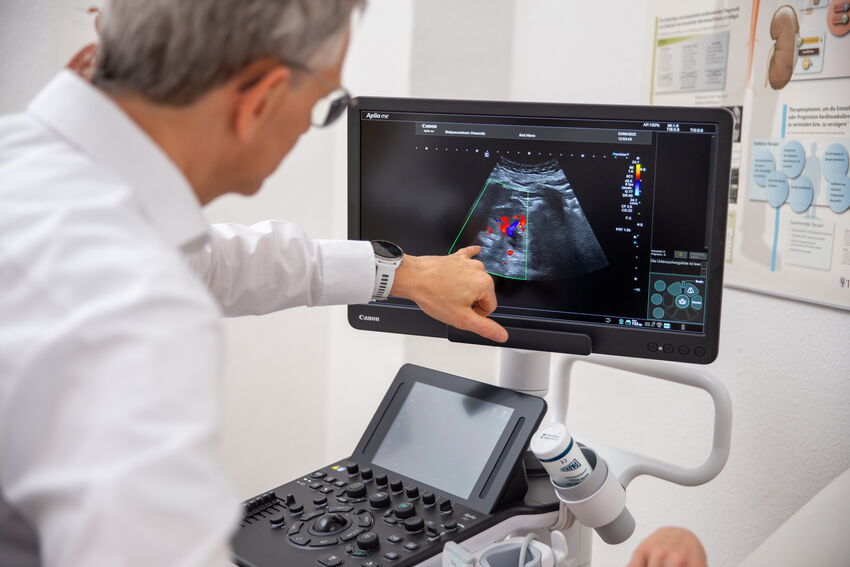 Dr. med. Jörg Schwöbel bedient ein Ultraschallgerät zur Gefäßdiagnostik. Die Darstellung auf dem Monitor zeigt farblich markierte Bereiche. Die Untersuchung erfolgt im Rahmen der Vorbereitung oder Kontrolle einer Dialysebehandlung.
