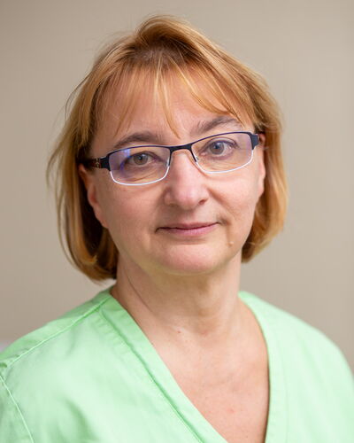 Pflegedienstleitung Silvana Karpati-Weinberg ist in grüner Dienstkleidung vor hellem Hintergrund porträtiert. Ihr ruhiger Blick und die klare Erscheinung stehen für Erfahrung und fachliche Sicherheit in der Pflegeleitung.