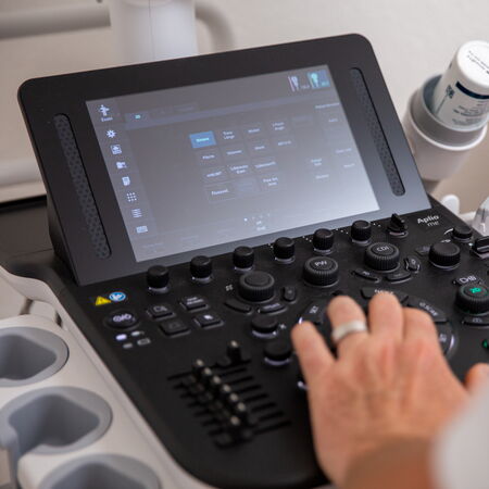 Dr. med. Markus Gläser bedient das Touch-Bedienfeld eines Ultraschallgeräts. Die Szene zeigt eine ruhige, klinische Situation.