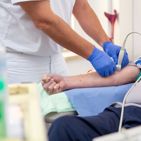 Dr. med. Andreas Sohn hält eine Ultraschallsonde auf den Arm eines Patienten. Die Szene zeigt eine klinische Kontrollsituation im Rahmen der Dialyseversorgung.